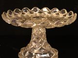 a glass cake plate on a table with a black background