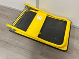 un gros plan d'un chariot à bagages jaune et noir posé sur un plancher en bois
