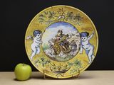 a plate with a painting on it next to an apple