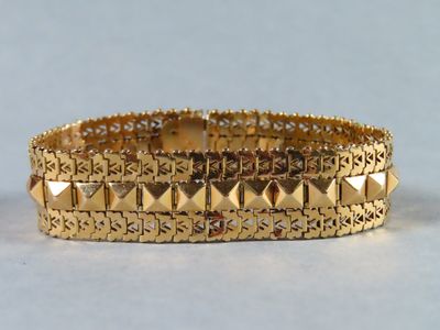 gros plan d'un bracelet en or sur une surface blanche