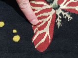 a hand that is touching a red and white butterfly on a black rug