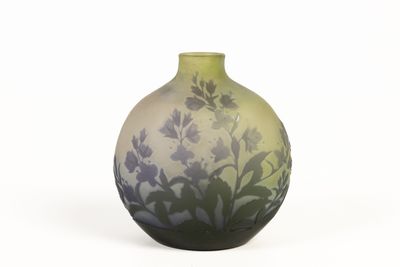 un vase vert orné de fleurs violettes, posé sur un fond blanc