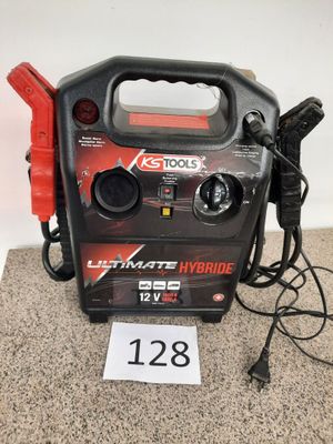 un chargeur de batterie portable noir et rouge posé sur un tapis