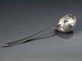 une cuillère en argent avec un manche de cuillère sur une surface grise
