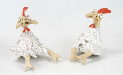 two figurines of a chicken that are sitting next to each other