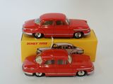 two red toy cars sitting next to each other on top of a yellow box