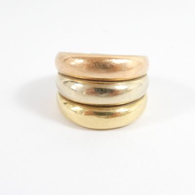 three gold rings stacked on top of each other on a white surface