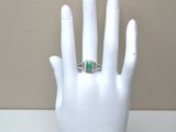 a hand with a ring on it that has a green stone in it