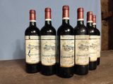 six bottles of wine are lined up on a wooden table