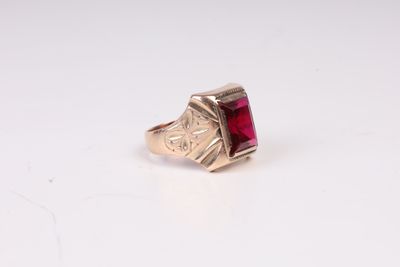 Gros plan sur une bague en or ornée d'une pierre rouge