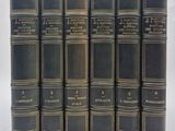 six vieux livres sont alignés sur une surface blanche