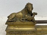 bronze statue of a lion resting on top of a wooden base