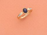 gros plan d'une bague en or avec un saphir et des diamants