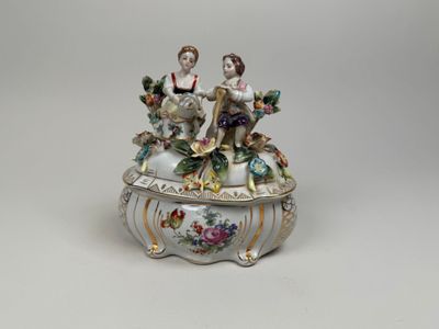 figurine en porcelaine représentant deux personnes assises sur une boîte