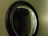 a round mirror hanging on the wall above a sink