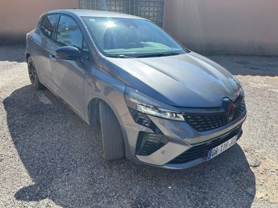 La voiture grise est garée sur le gravier près d'un bâtiment.