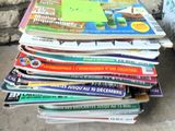 une pile de magazines posée par terre à côté d'une poubelle