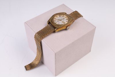 une montre en or posée sur un coffret rose