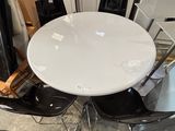 a white table with four black chairs around it
