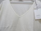 white v - neck sweater hanging on a hanger with a tag on it