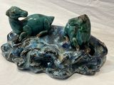 a ceramic figurine of two animals on a rock
