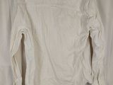 a white shirt hanging on a hanger in front of a curtain