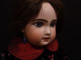 a close up of a doll sitting on a black surface