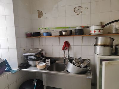 Les casseroles et les poêles sont posées sur le plan de travail dans une petite cuisine.