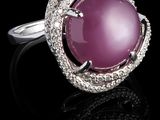 une photo d'une bague en jade rose et diamants posée sur un fond noir