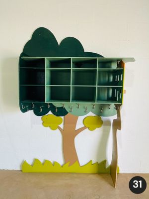 une étagère verte sur laquelle se trouve un arbre, à côté d'un mur blanc