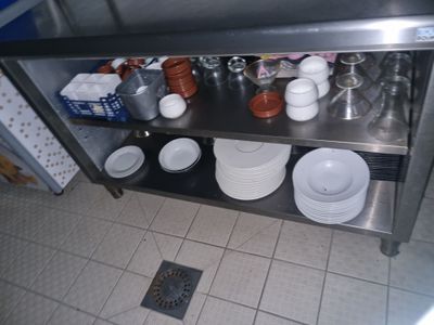 une étagère en acier inoxydable sur laquelle sont posées des assiettes et des tasses