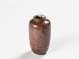 a brown vase sitting on a white table with a black background