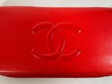 un sac à main Chanel rouge posé sur une surface blanche