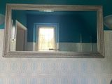 un miroir sur le mur au-dessus d'un lavabo dans une salle de bains