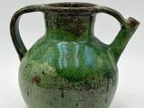 a green vase that is sitting on a white surface