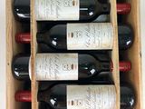 bottles of red wine in a wooden box on a white surface