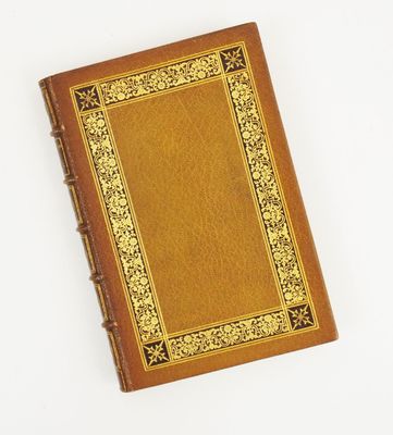 un vieux livre à la couverture dorée posé sur une surface blanche