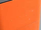 an orange trash can with a black top on the street