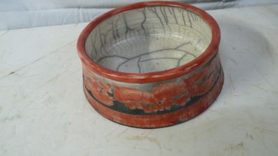 un bol rouge et noir posé sur une surface blanche