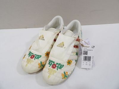 pair of adidas shoes with flowers on them sitting on a white surface