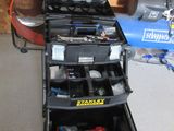 une boîte à outils contenant des outils, posée sur le sol