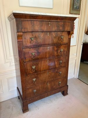 a wooden chest of drawers with marble top in a room