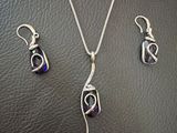 a silver necklace and earring set on a black leather surface