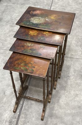 trois tables en bois ornées de fleurs peintes, posées sur un sol en béton