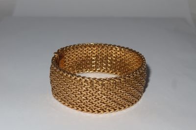 a close up of a gold bracelet on a white surface