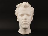 a white sculpture of a man ' s head on a black surface