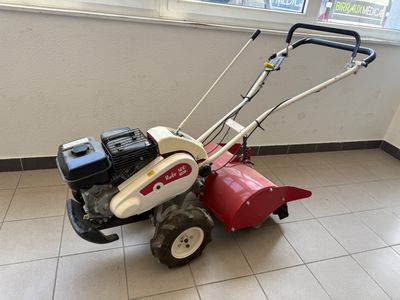 une petite tondeuse à gazon rouge et blanche posée par terre