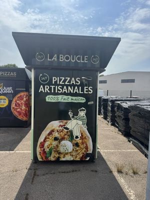une affiche faisant la promotion de pizzas et de produits artisanaux dans un parking
