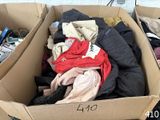 une boîte en carton remplie de vêtements et des vêtements posés par terre