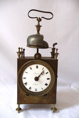une horloge surmontée d'une cloche, sur fond blanc
